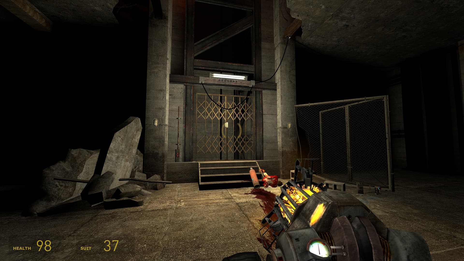 A screenshot of Half-Life 2: Episode One. The player stares at the elevator at the end of the chapter Lowlife, with a single light still on above the elevator while half a zombie corpse lies beneath, next to a large bloodstain.