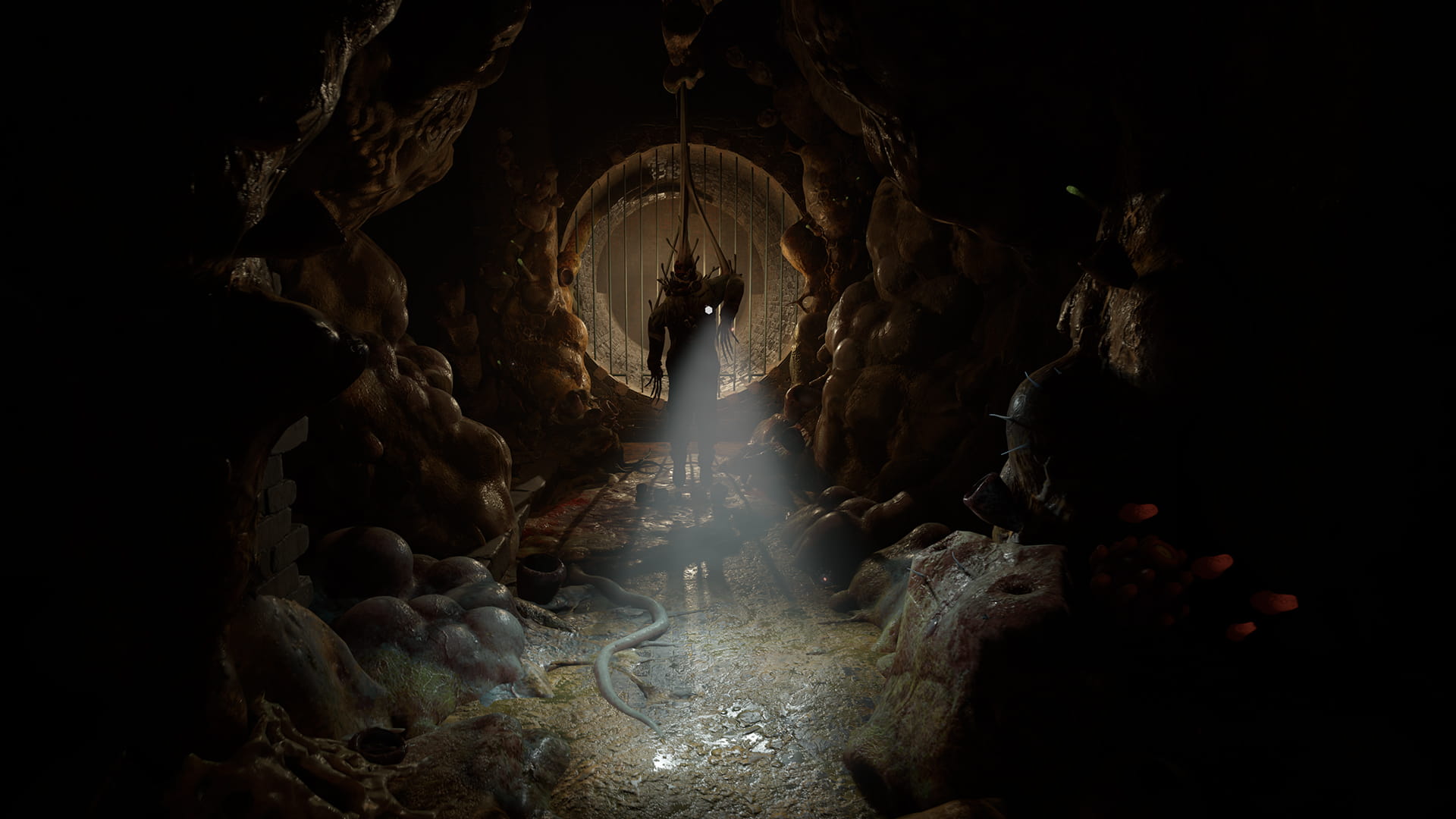 A pre-release screenshot of Half-Life: Alyx. A corpse dangles from above with a flashlight attached to it, surrounded by bulbous alien fungi.